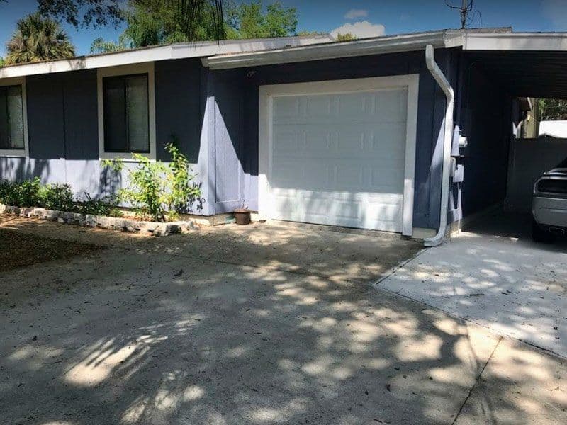 Exterior view of a blue house with a garage, driveway, and parked car.