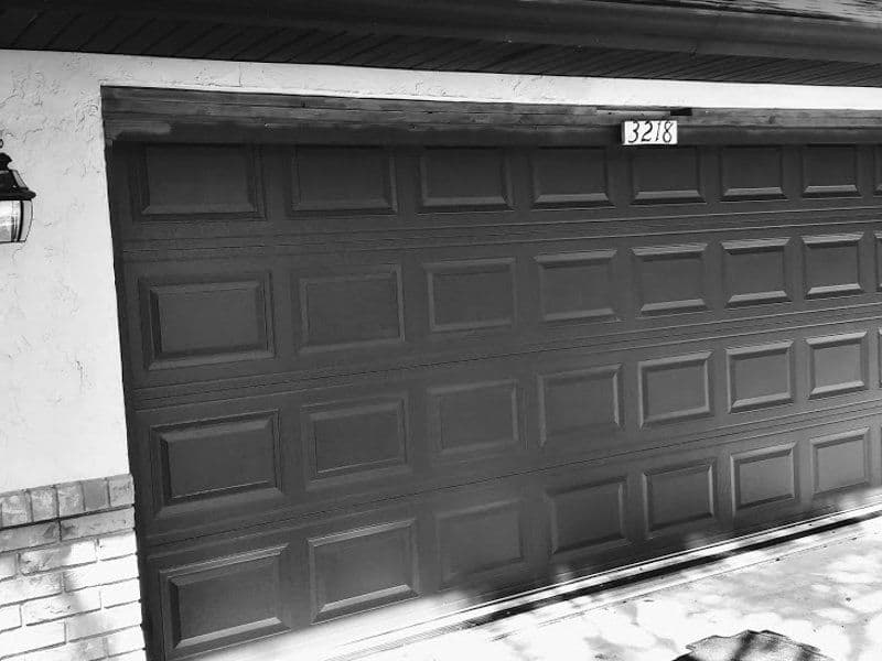Black garage door with textured panels, house number 3218 visible above.