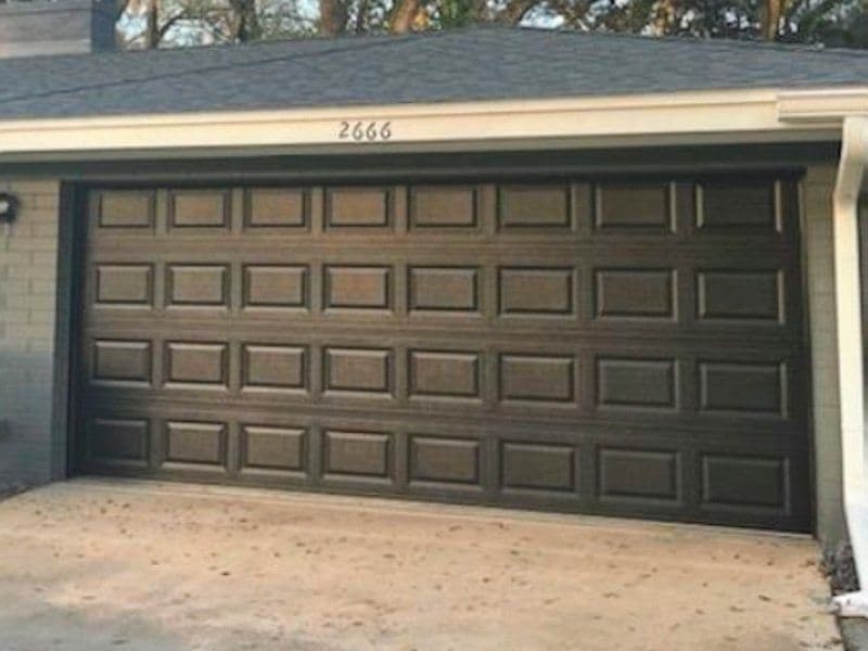 Modern dark brown garage door with rectangular panel design, residential home exterior.