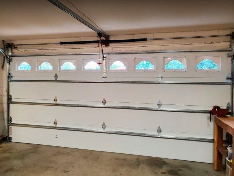 Garage door with windows, featuring a clean white finish and metal framing. Ideal for home spaces.