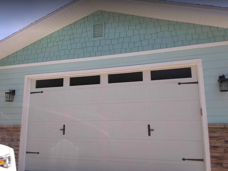 White sectional garage door with decorative window panels installed on a home.
