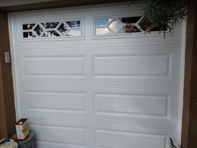 White garage door with decorative window panels installed on a residential home.